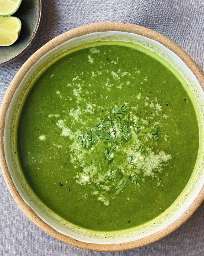 Smooth green soup sprinkled with parmesan and parsley 