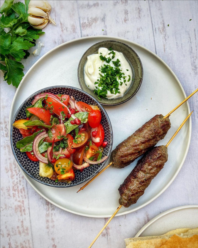 Fried beef koftas served alongside fresh yoghurt and a colorful salad of tomatoes, onions, greens and pomegranate jewels on A Flavour Affair & All Recipes Category