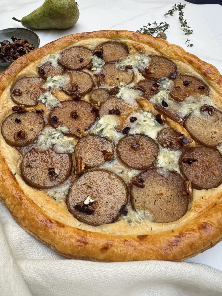 Pear and gorgonzola round puff pastry tart with round slices of caramelized pears