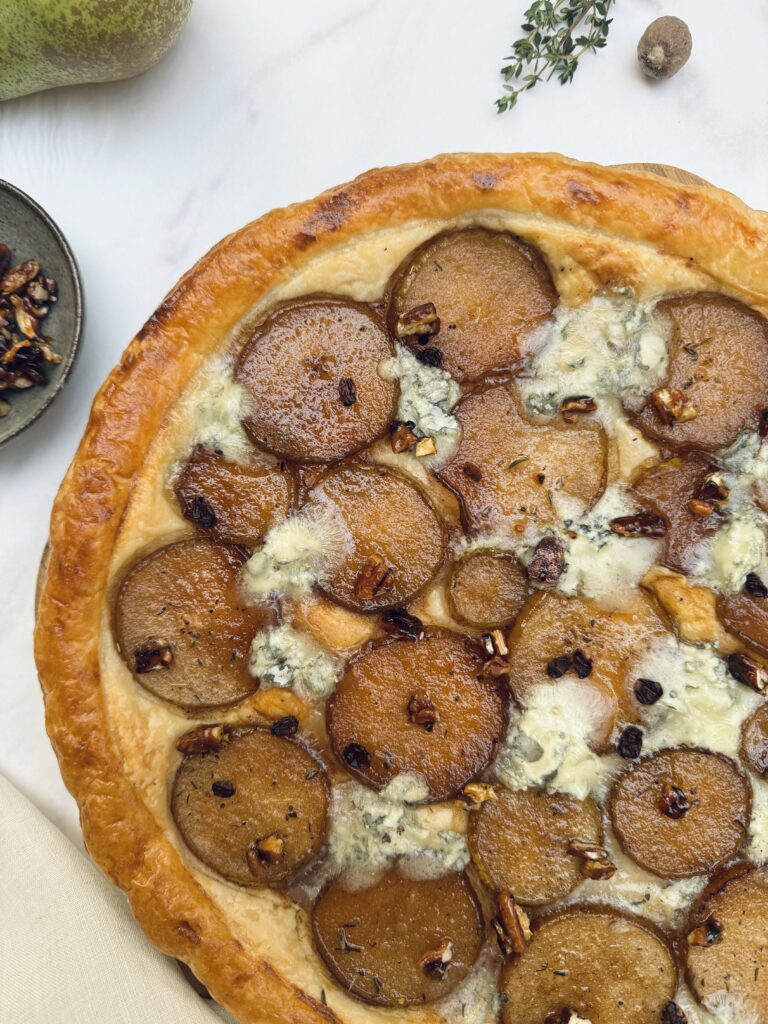 Pear and gorgonzola round puff pastry tart with round slices of caramelized pears