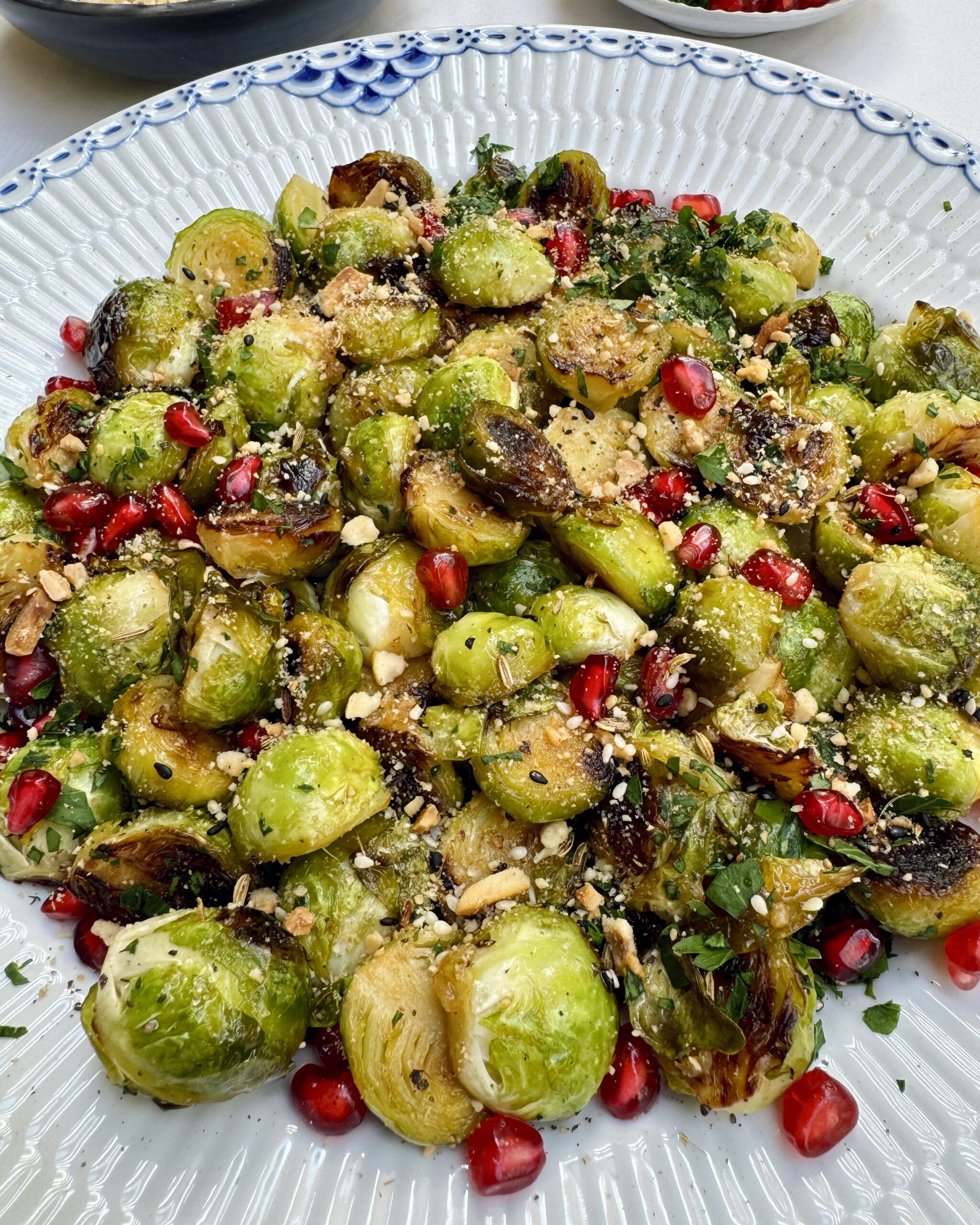 Golden brown brussels sprouts topped with nuts and pomegranate jewels