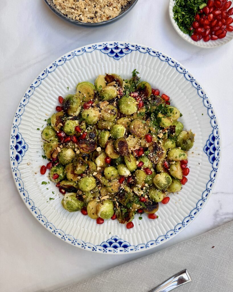 pan-fried brussels sprouts topped with nuts and pomegranate seeds 