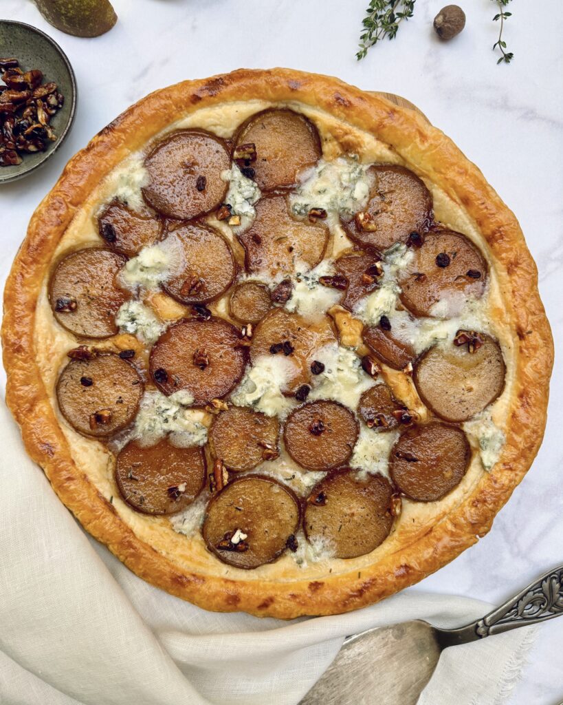 Pear and gorgonzola round puff pastry tart with round slices of caramelized pears