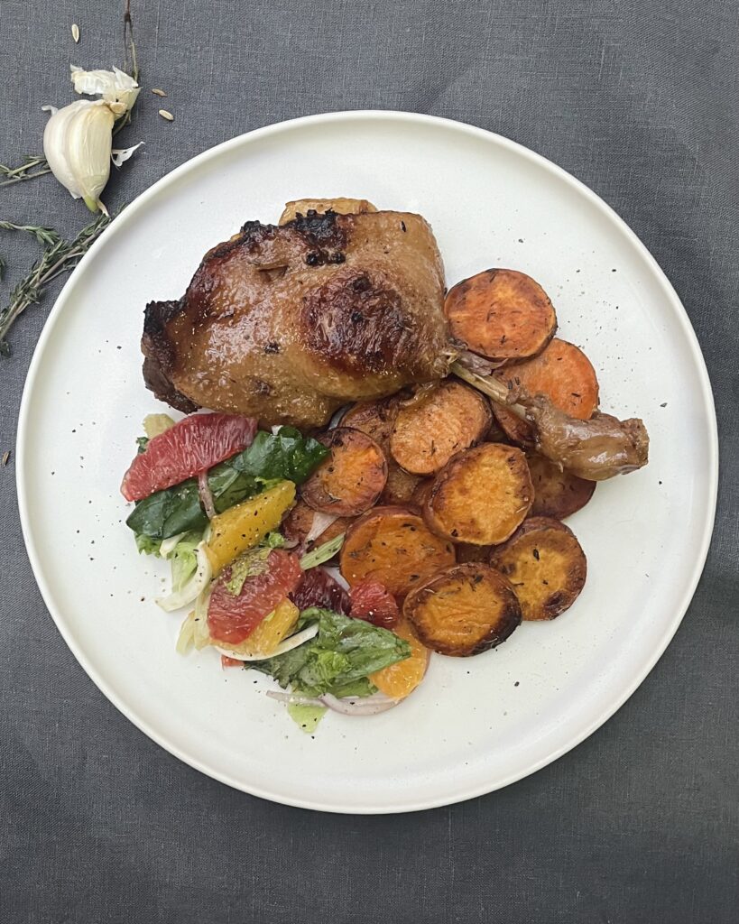 Braised duck leg with sliced sweet potatoes and a citrus salad