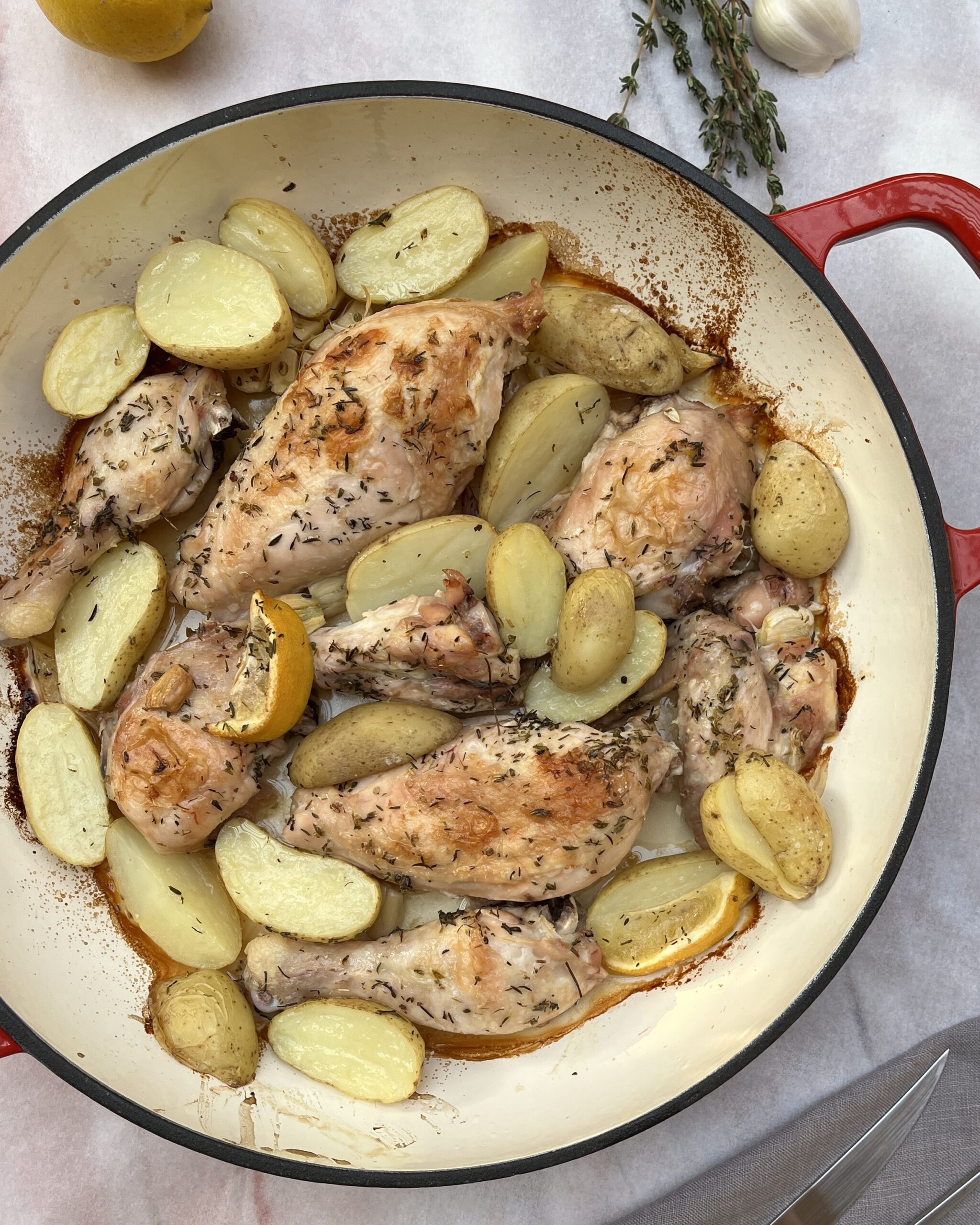 Chicken parts in a casserole with herbs and golden potatoes