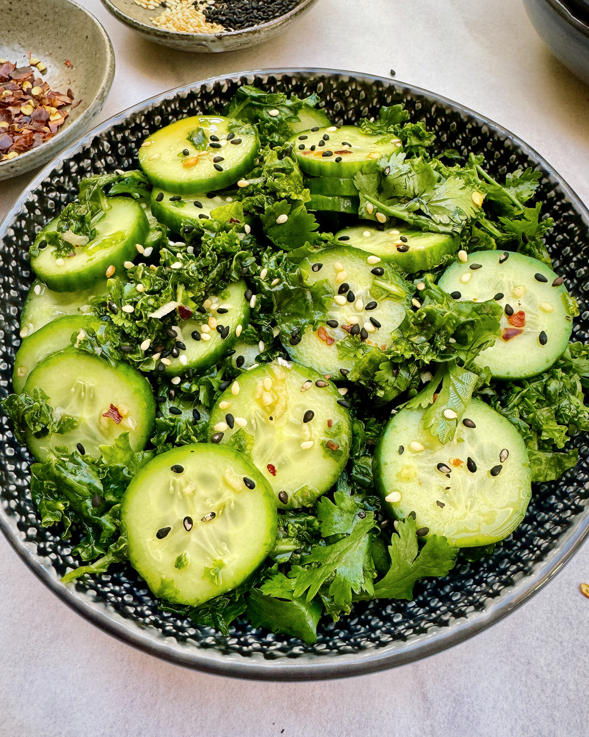 cucmber and kale salad with nuoc cham dressing, sesame seeds and fresh coriander