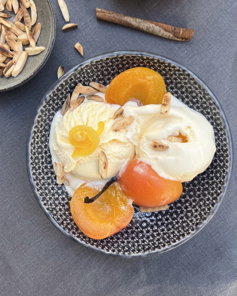 a bowl with two scoops of vanilla ice cream with poached apricots