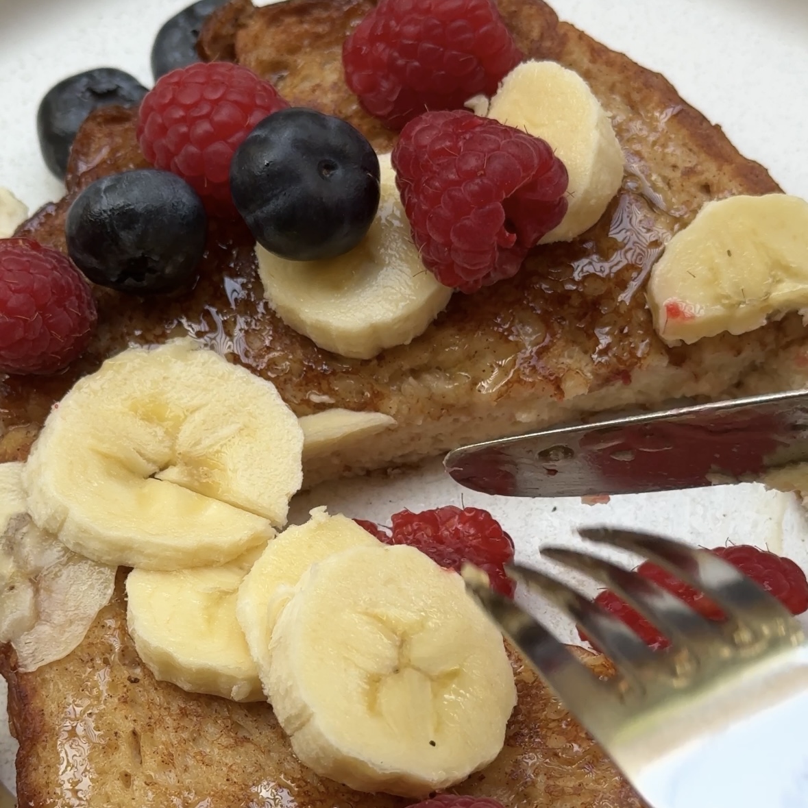 Golden French toast drizzled with honey and topped with berries and banana slices