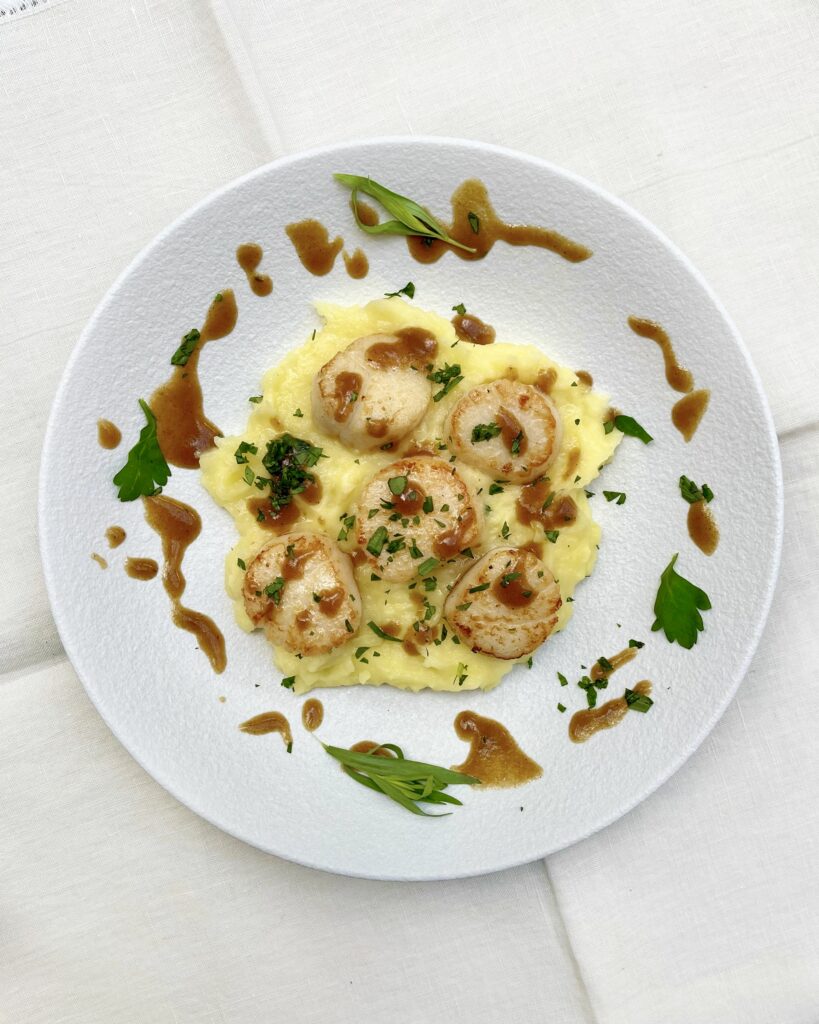 Golden seared scallops over mashed potatoes with browm muchroom sauce and fresh herbs