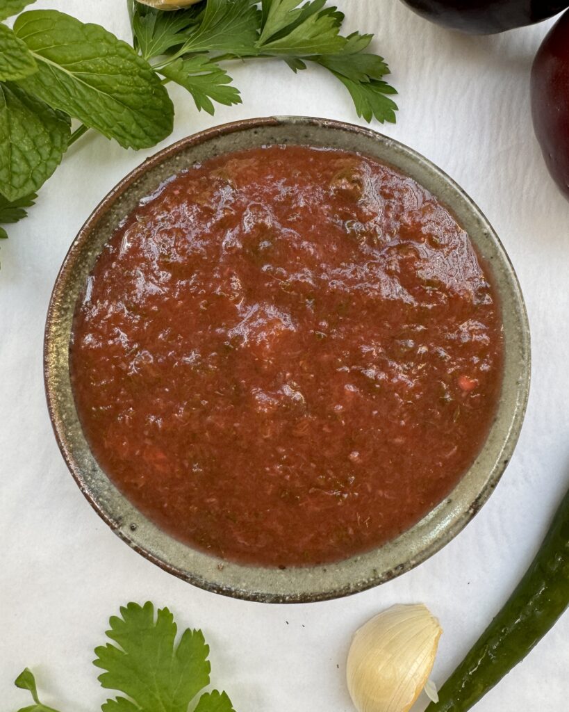 A bowl with tkemali, plum sauce with herbs and aromatcis