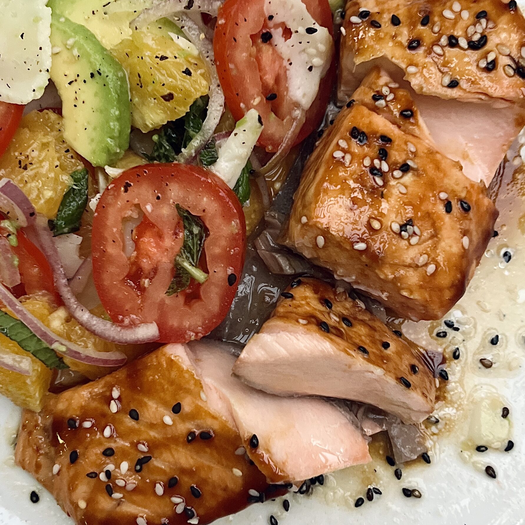 Baked salmon fillet coated with a glossy orange glaze and topped with sesame seeds