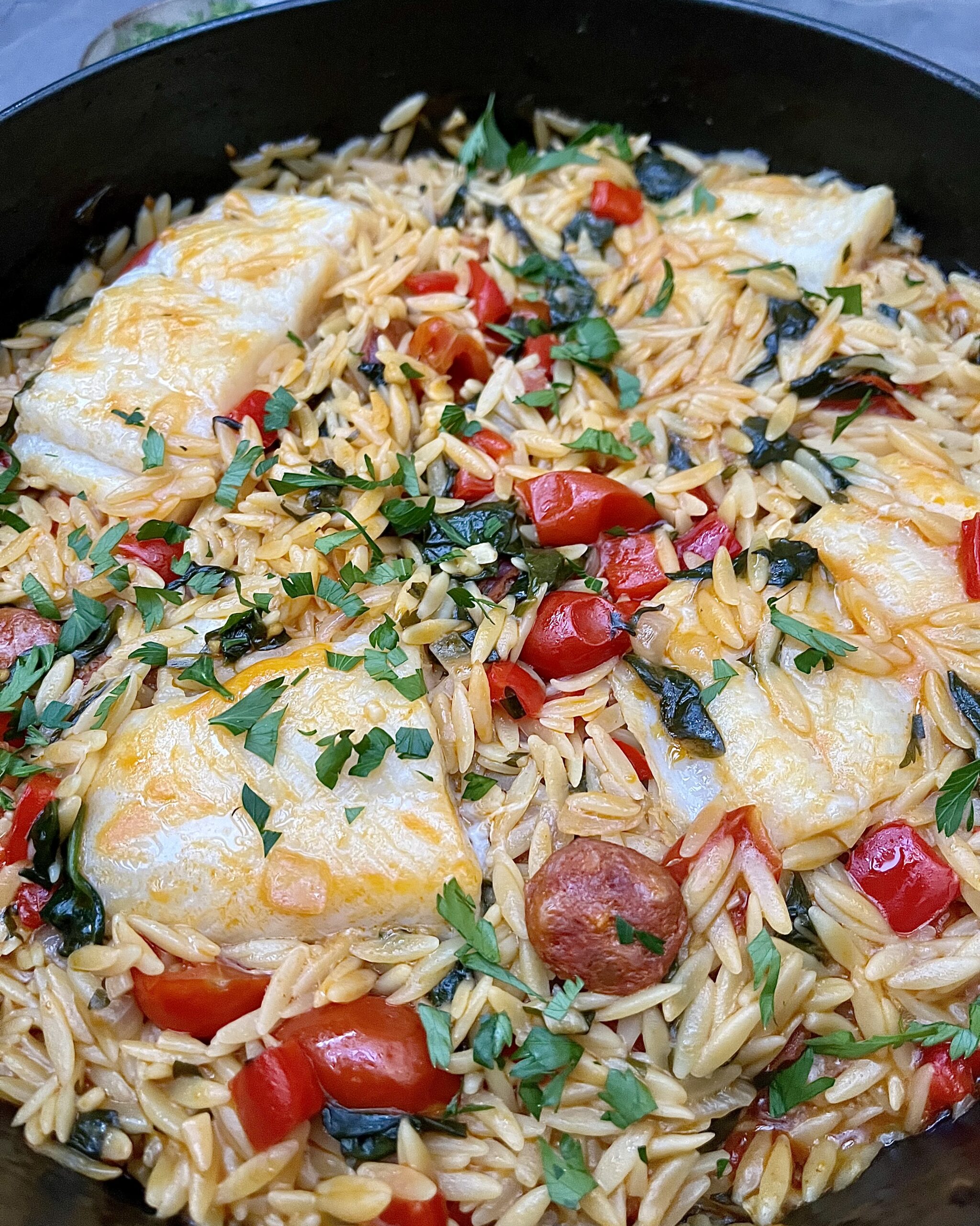 orzo pasta in red tomato sauce with chorizo, bell peppers and white fish