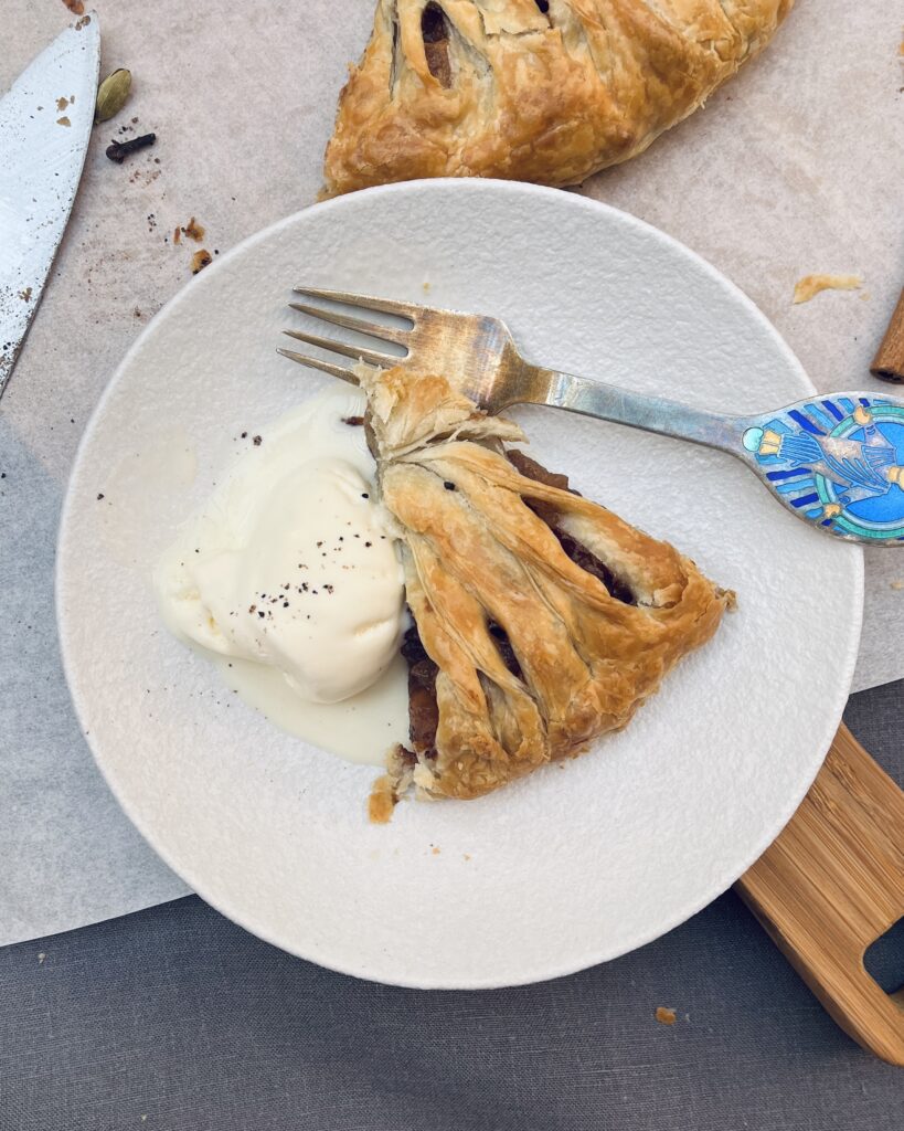 A slice of Apple Strudel with dark red filling and a scoop of ice cream