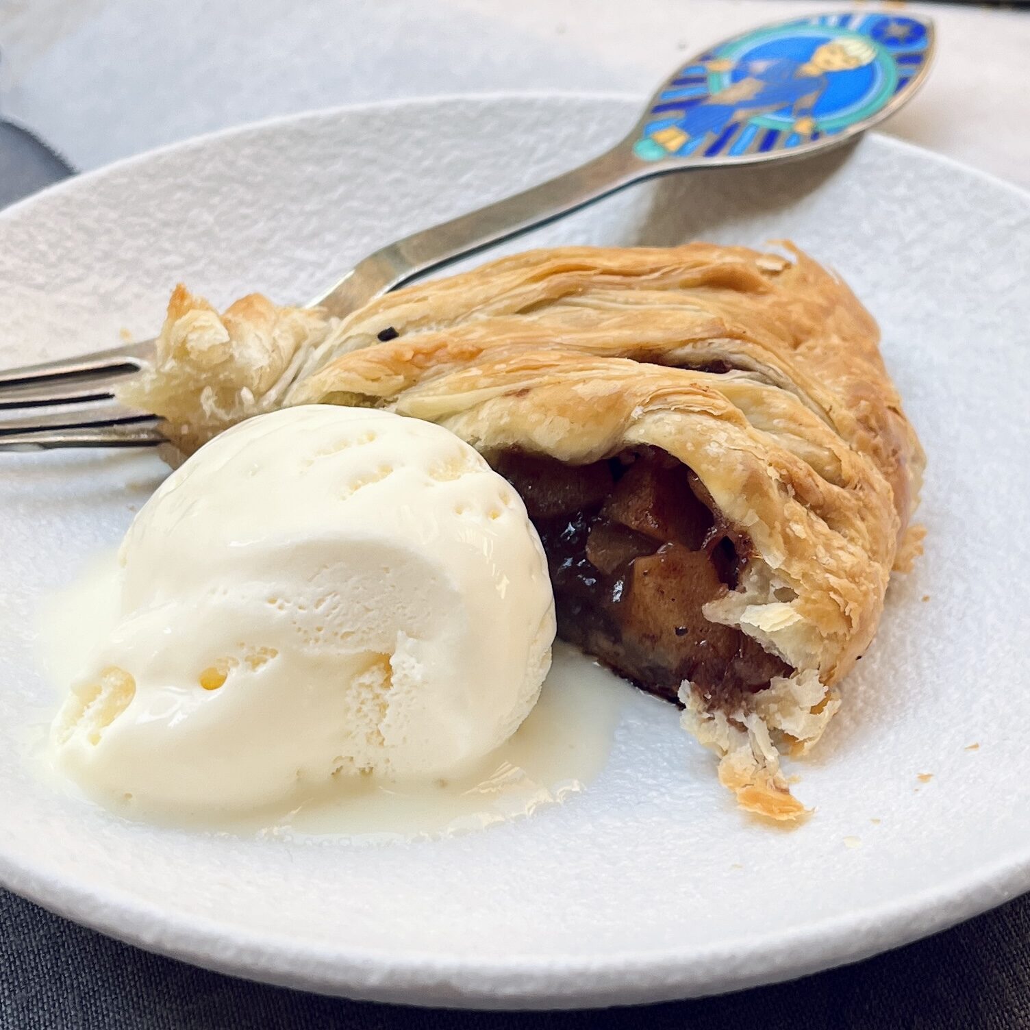 A slice of Apple Strudel with dark red filling and a scoop of ice cream