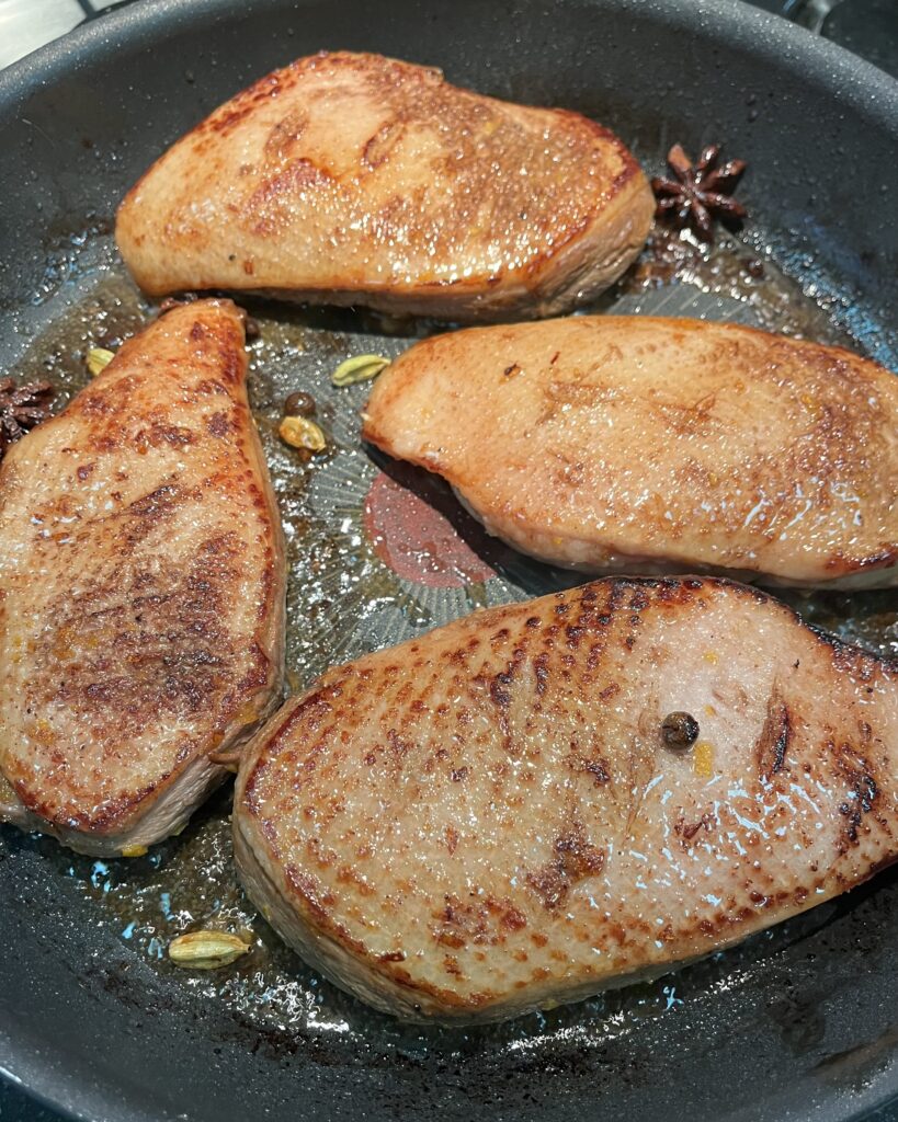 duck breasts getting seared on a pan