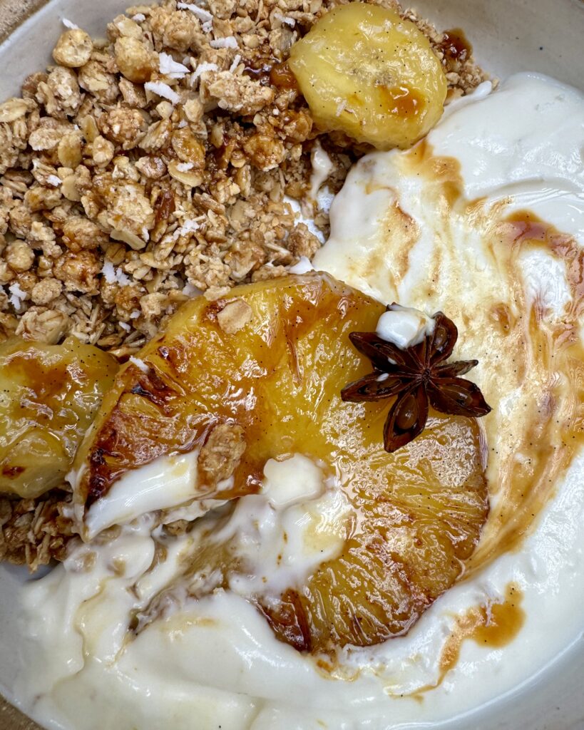 caramelized pineapple in a bowl with yoghurt and granola and slices of banana