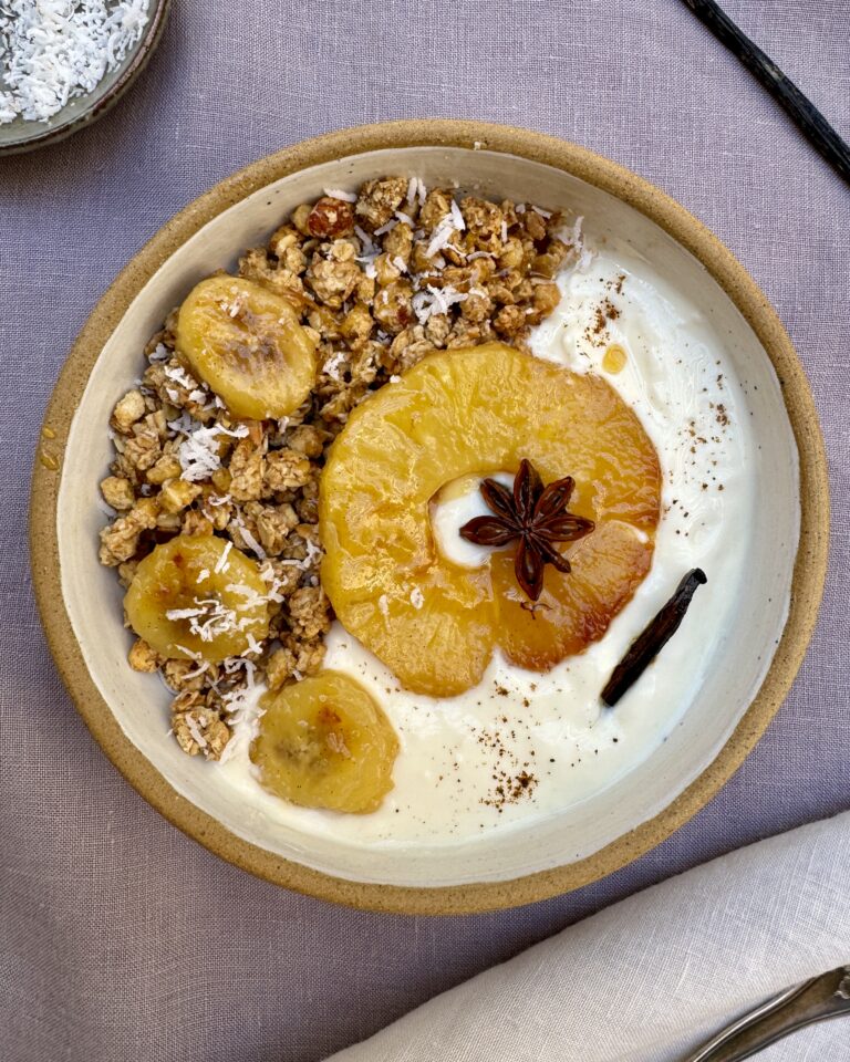 A bowl with yoghurt and granola topped with caramelized pineapple and coconut shavings