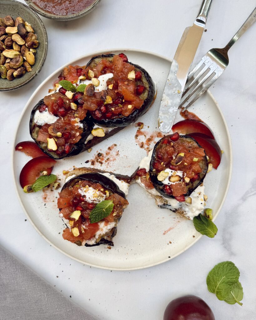 fried eggplant toast with diced tomatoes and burrata topped with pomegranate jewels and pistachios