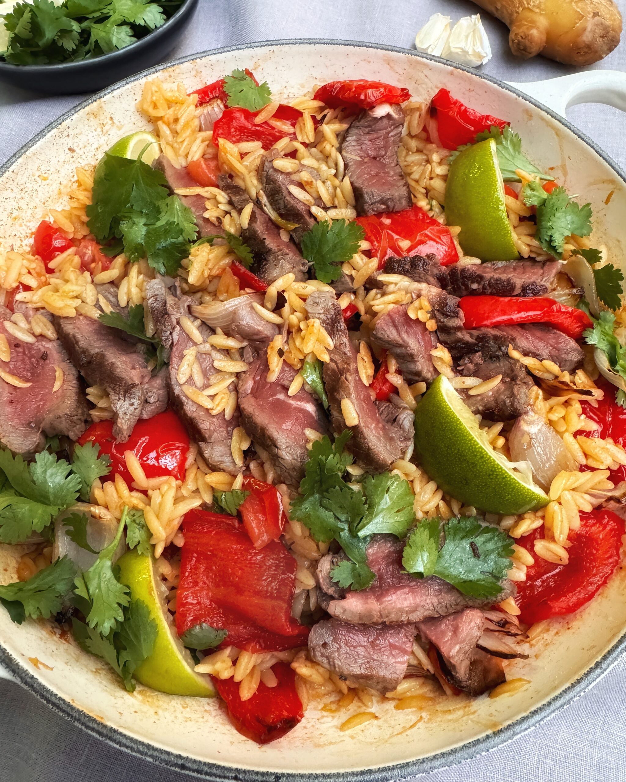 A casserole with Steak and Orzo cooked with Jamaican Jerk, Ginger and Garlic, red bell peppers and coriander leaves