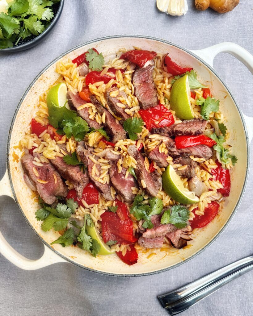 A casserole with Steak and Orzo cooked with Jamaican Jerk, Ginger and Garlic, red bell peppers and coriander leaves