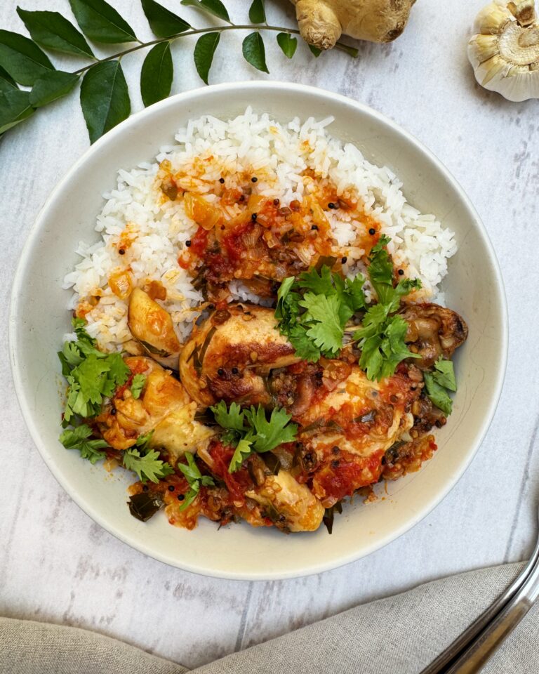 Chicken drumsticks curry in a rich tomato sauce with black and yellow mustards seeds, curry leaves and onions served over white rice