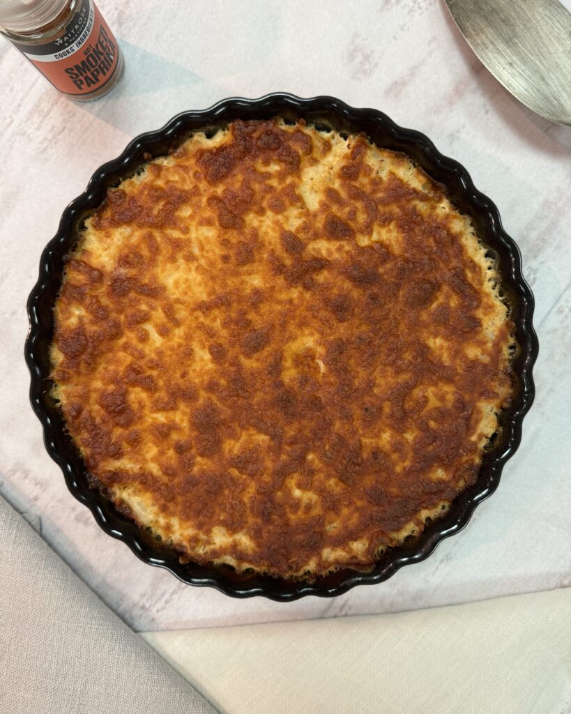 A round black baking dish with Cauliflower gratin under golden cheese crust