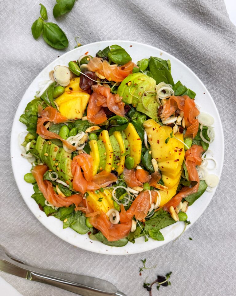 A plate of Smoked Salmon with Mango and Avocado, edamame, leeks and salad greens