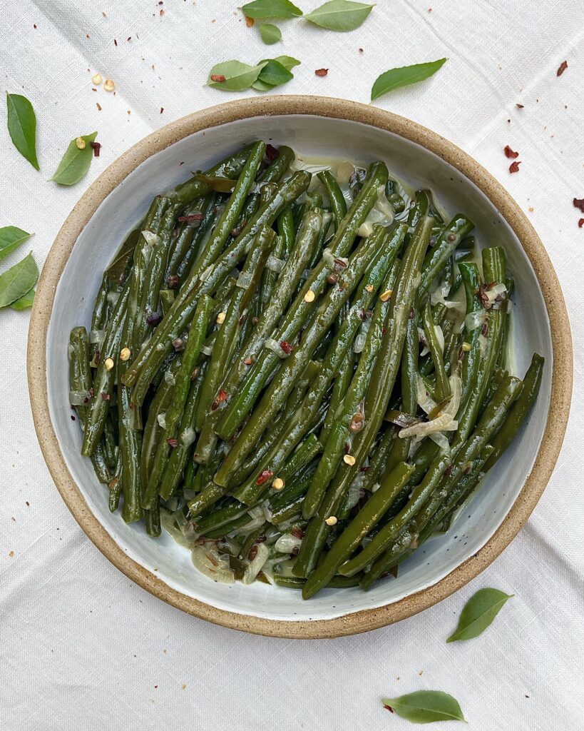 a bowl with green beans in coconut gravy with red chili flakes