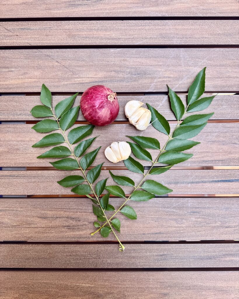 a set of aromatics - red onion, garlic and curry leaves