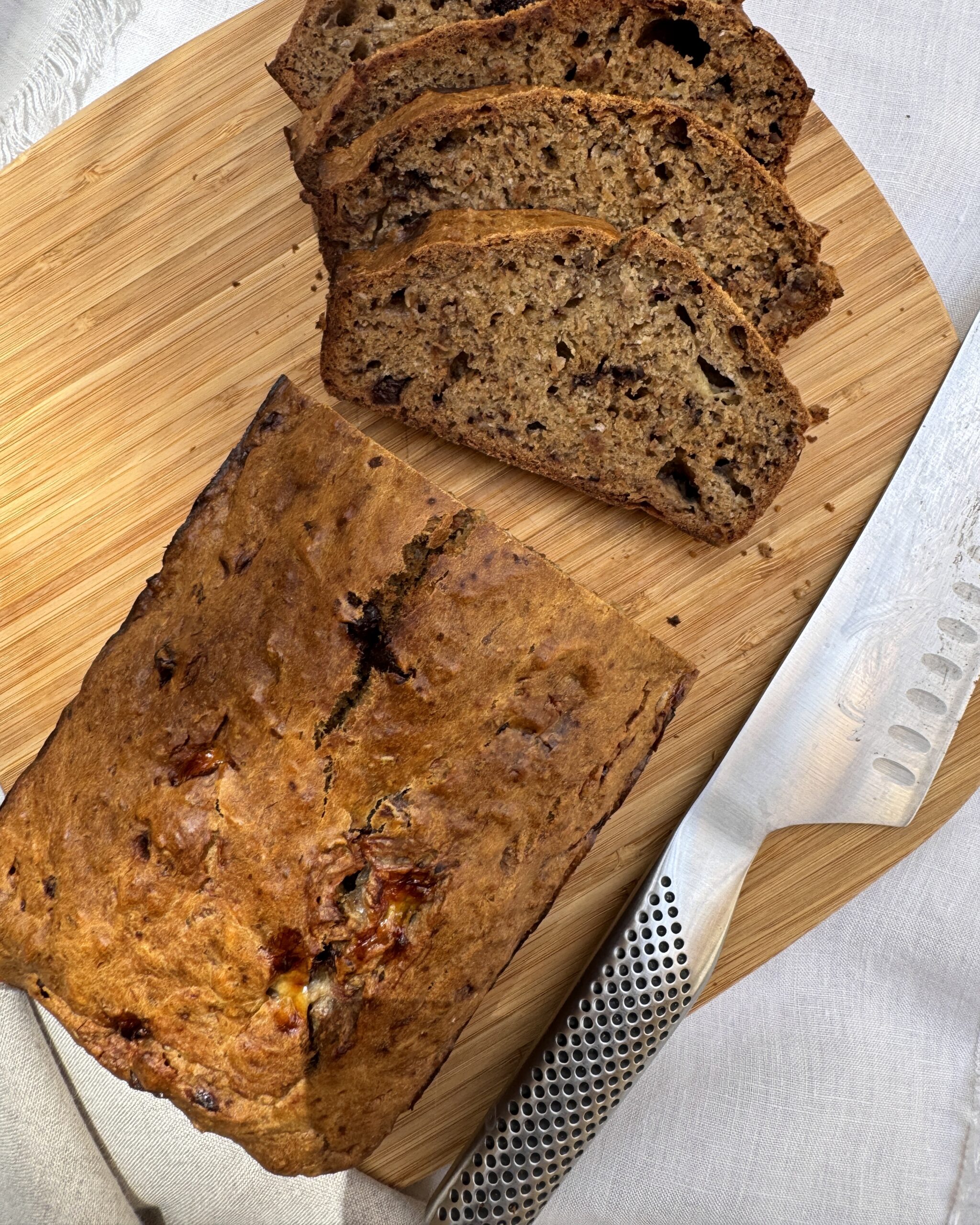 banana bread loaf on a wooden board with some slices cut