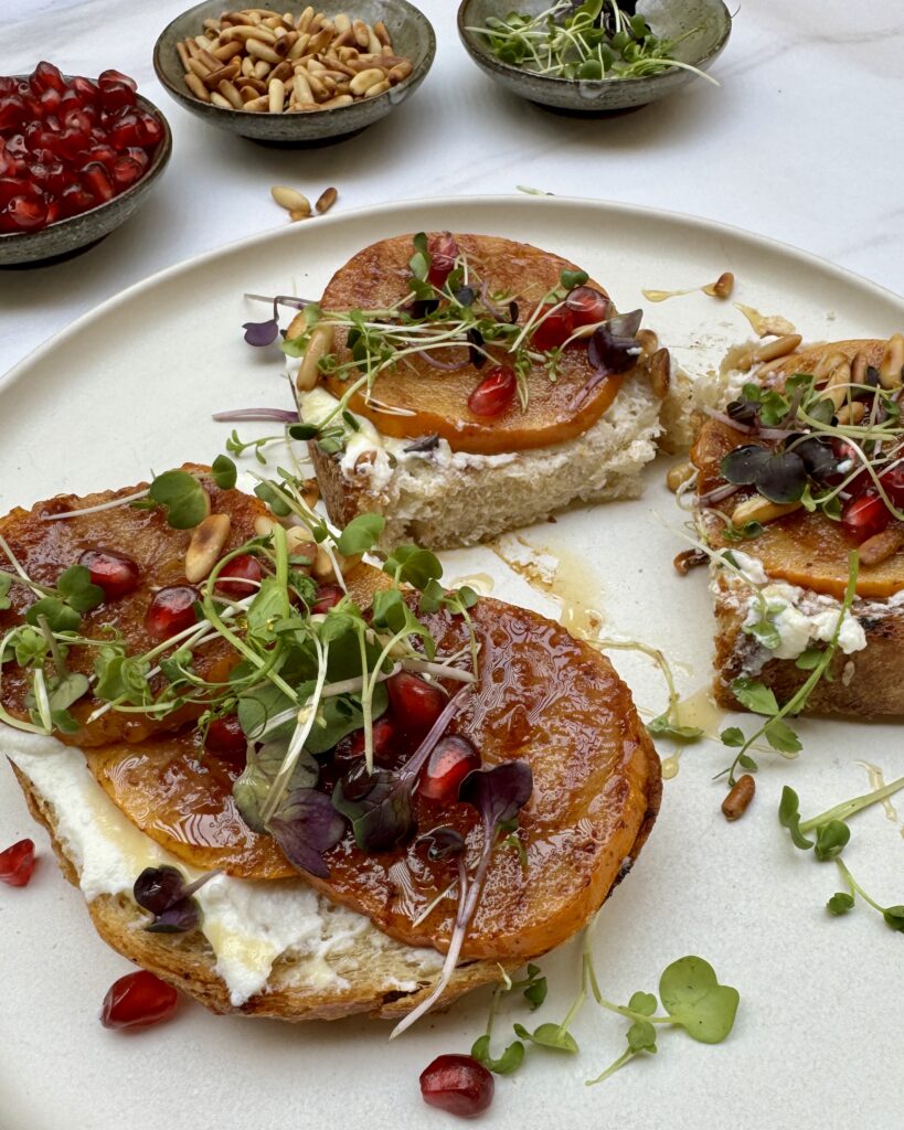 a close up on a plate with two grilled sourdough toasts with persimmons and whipped ricotta