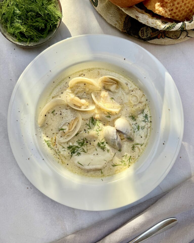 a plate with creamy seafood soup with clams, white fish, leeks, celery, saffron and dill