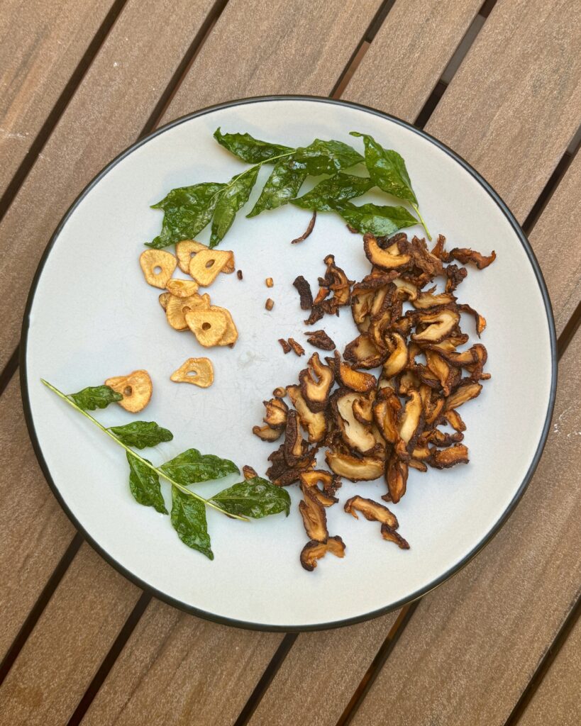 a plate with toppings - crispy curry leaves, fried shiitake caps and garlic chips