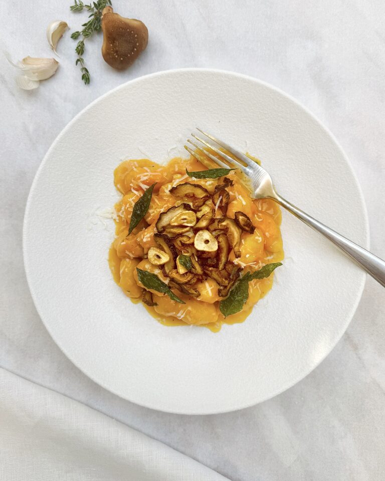 A plate of Gnocchi in Squash Sauce with fried mushroom caps, garlic chips and crispy curry leaves