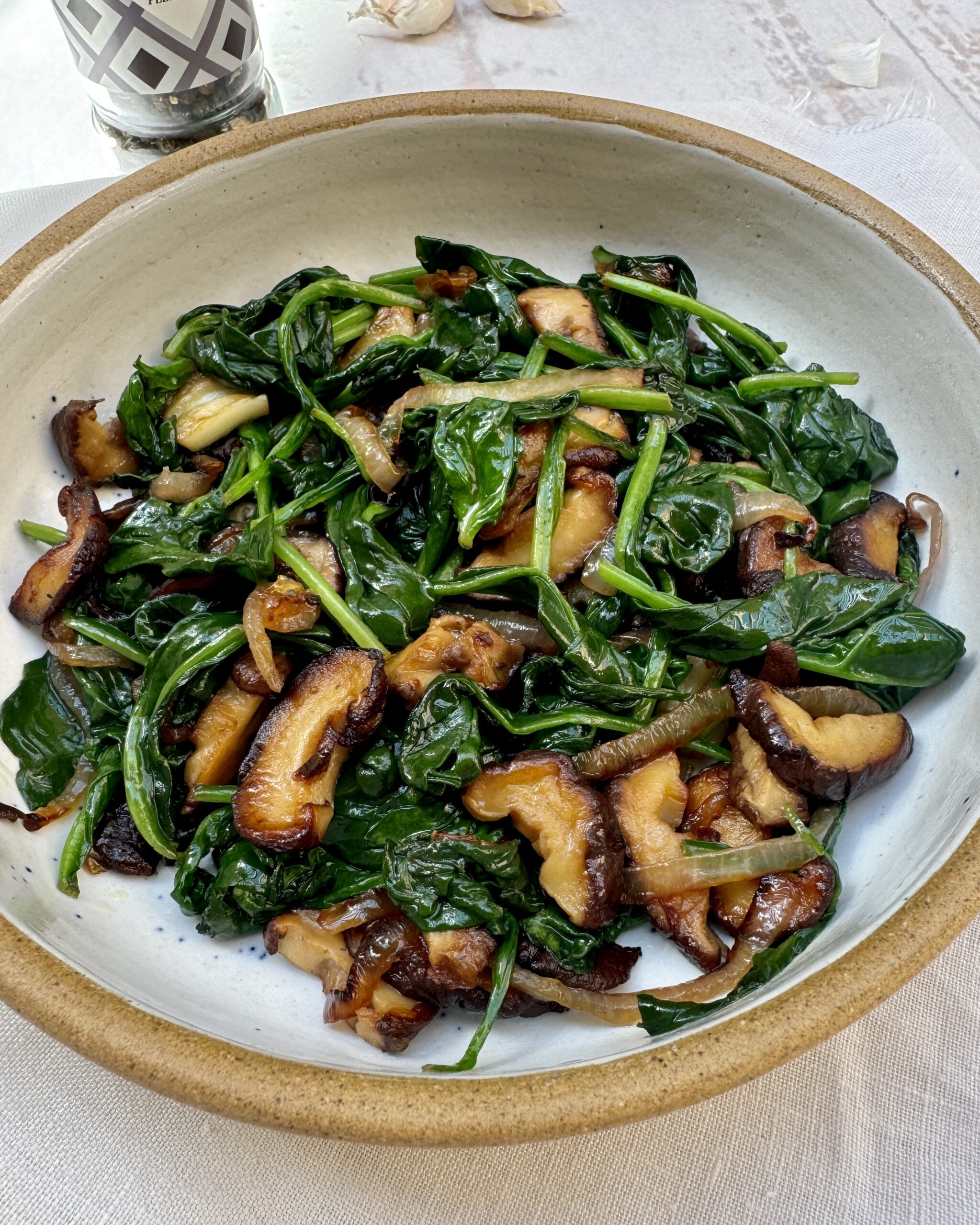 a plate with quick buttery spinach mixed with fried onions, garlic and shiitake mushrooms