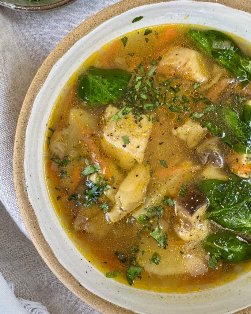 a close up on a bowl with Mushroom soup with king bolete, potatoes, spinach, garnished with parsley