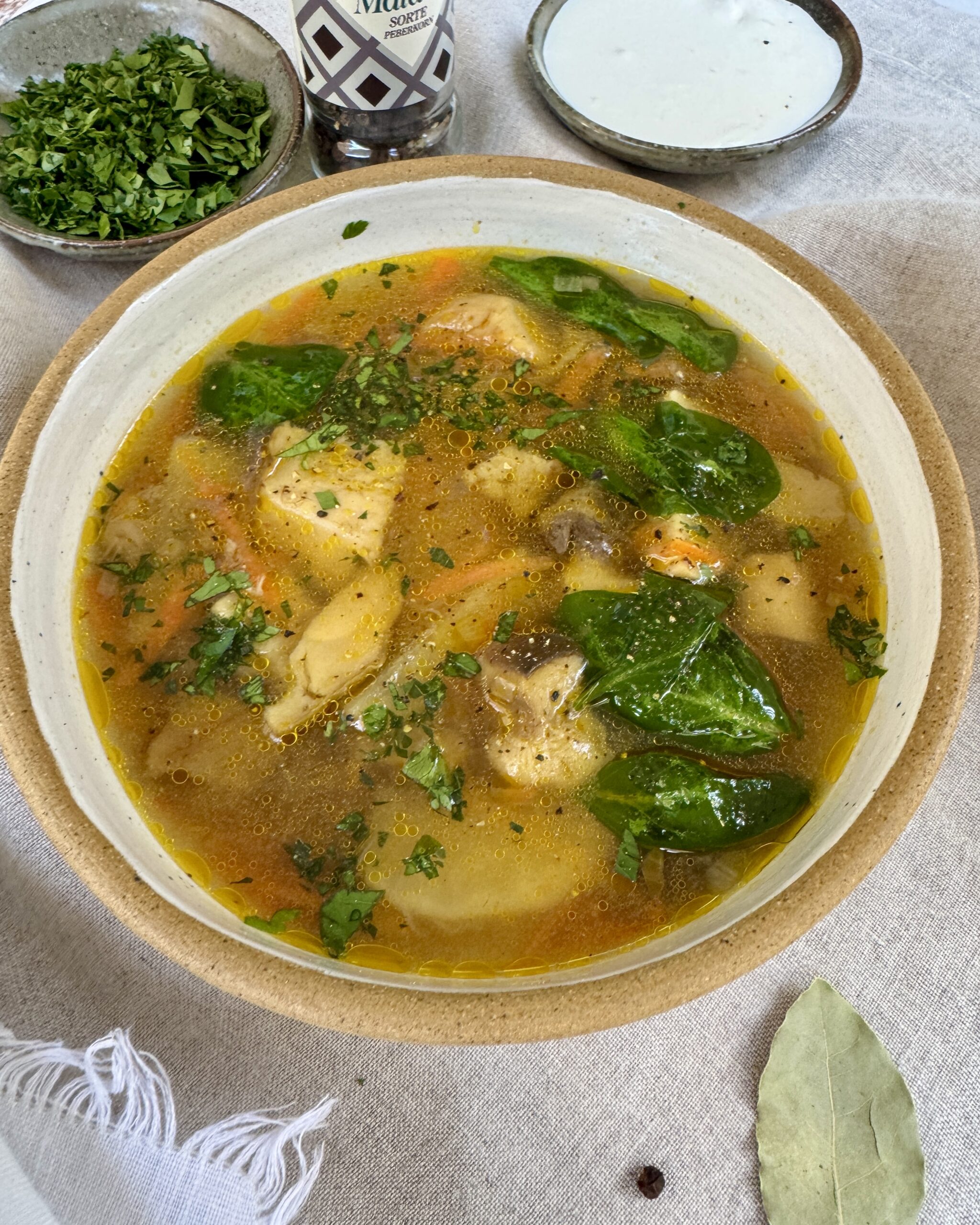 a bowl with Mushroom soup with king bolete, potatoes, spinach, garnished with parsley