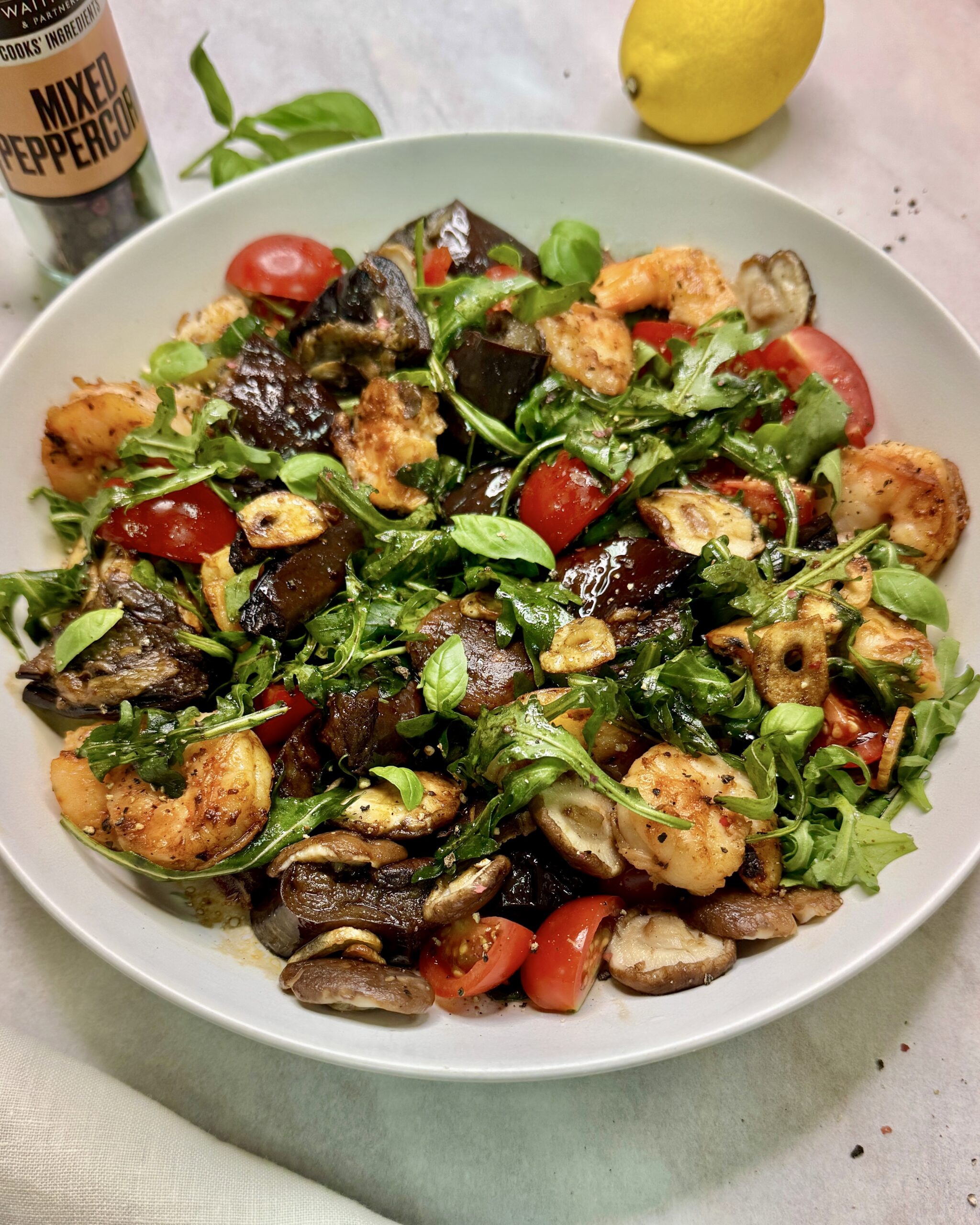 a plate with Prawn Salad with fried eggplant, shiitake mushrooms, garlic chips, tomatoes and greens