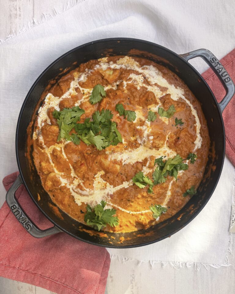 a pot with chicken tikka masala garnished with cream and cilantro