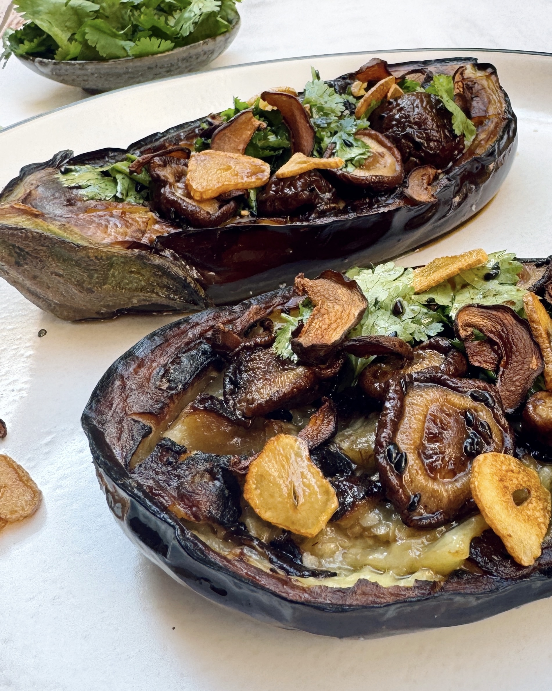 Eggplant halves stuffed with a mixture of garlic chips, shiitake and coriander with sesame truffle dressing