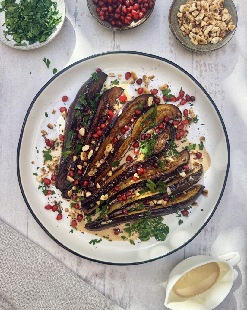 a plate with Fried eggplant with almond butter sauce, pomegranate, almonds and parsley
