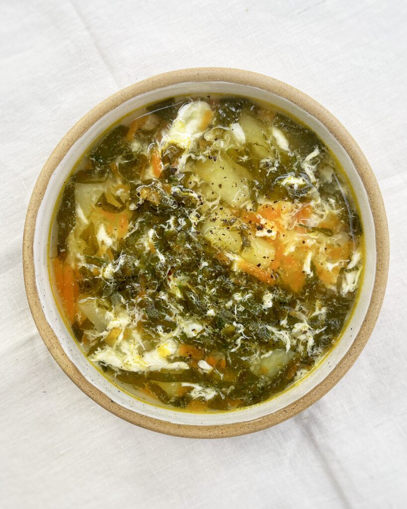 a bowl with sorrel soup with potatoes and egg ribbons